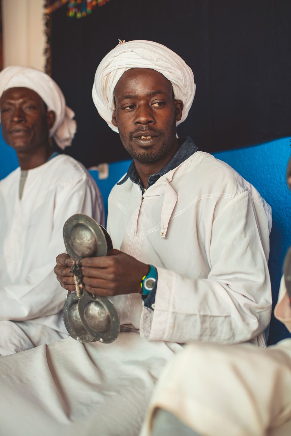 A Gnawa musician in traditional dress holding his instruments in Merzouga