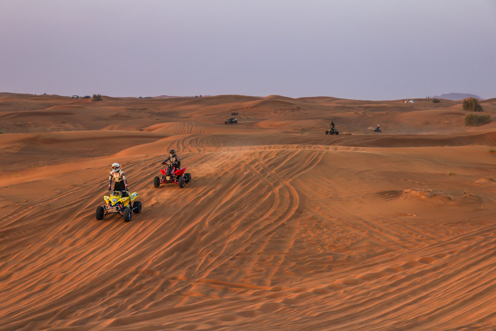 Riders exploring the desert dunes on quad bikes